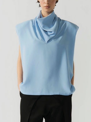 #sky-blue Person wearing a light blue sleeveless top with a cowl neck on a plain background