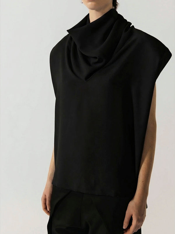 #black Person wearing a black sleeveless top with a draped design on a plain background
