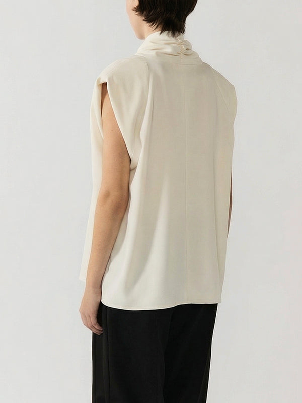 #off-white Person wearing a beige sleeveless top and black pants on a white background